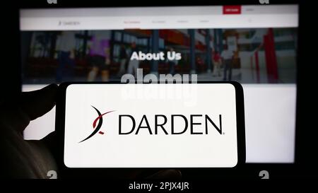 Person holding smartphone with logo of US gastronomy company Darden Restaurants Inc. on screen in front of website. Focus on phone display. Stock Photo