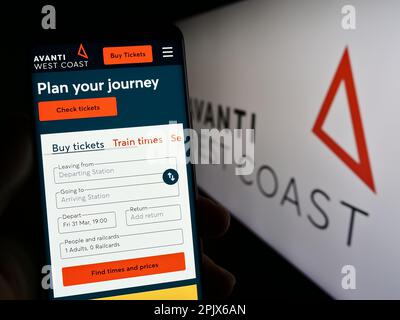 Person holding cellphone with website of British train company Avanti West Coast on screen in front of logo. Focus on center of phone display. Stock Photo