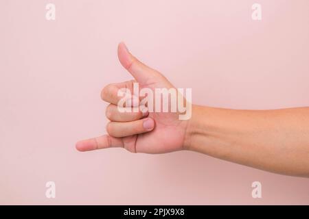 Call me hand sign or gesture isolated on pink background. Stock Photo