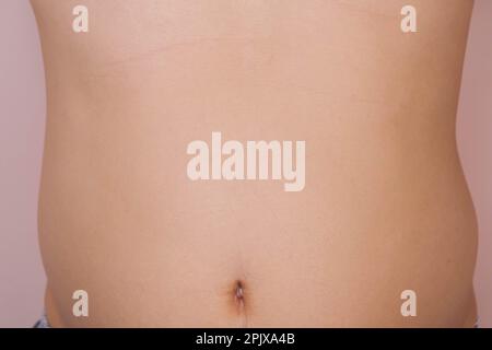 Man showing his fat belly isolated on pink background. Overweight young man with big belly Stock Photo