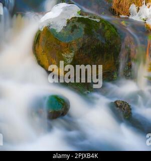 Close-up of a stream in the forest in winter with some snow and ice Stock Photo