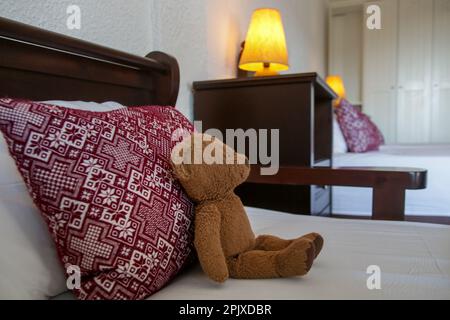 Retro bedroom style with red pattern pillows and brown teddy bear on bed Stock Photo