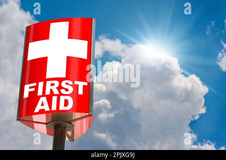 Close-up of a modern red and white First Aid Sign against a clear blue sky with clouds and sunbeams. Photography. Stock Photo