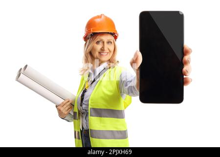 Female engineer with a safety vest and hardhat holding blueprints and showing a smartphone isolated on white background Stock Photo