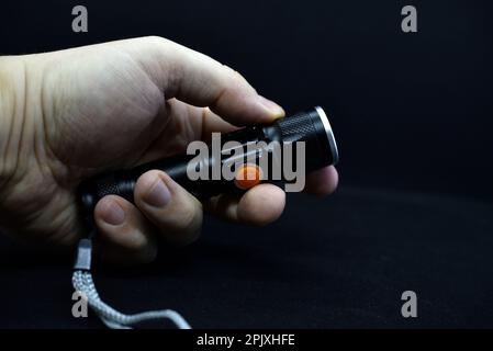 Metal black flashlight in hand. Pocket flashlight. Stock Photo