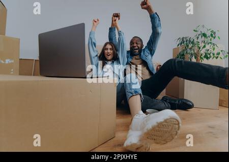 Young couple using laptop in their new house on moving day Stock Photo