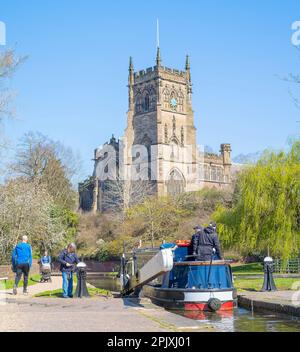 Kidderminster, UK. 4th April, 2023. UK weather: plenty of spring sunshine and blue skies makes for a perfect day on the water. A family and friends are all aboard their canal boat as they pass through a lock with St Mary's Church in Kidderminster in the background. Credit: Lee Hudson/Alamy Live News Stock Photo