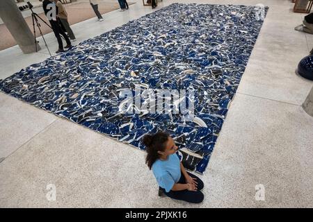 London, UK.  4 April 2023. A staff member with 'Left Right Studio Material', 2018, at a preview of ‘Ai Weiwei: Making Sense’, the artist’s first exhibition to focus on design and architecture.  Some of the Ai Weiwei’s most important works are displayed alongside collections of objects that have never been seen together with new commissions made for the exhibition.  The works are on show at the Design Museum 7 April to 30 July 2023.  Credit: Stephen Chung / Alamy Live News Stock Photo