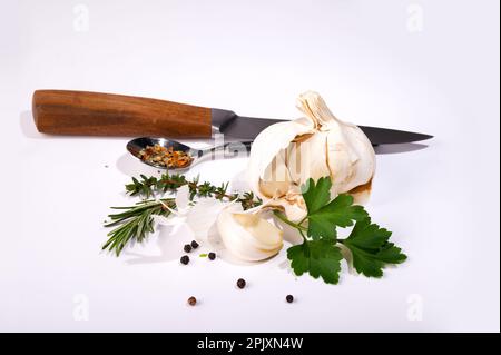 Garlic parsley rosemary and thyme separated with knife on white background Stock Photo