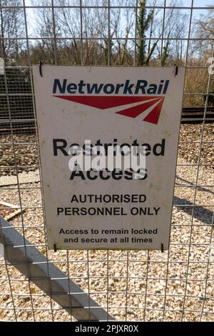 Network Rail warning signs fixed to a metal fence alongside a railway line Norfolk England UK Stock Photo