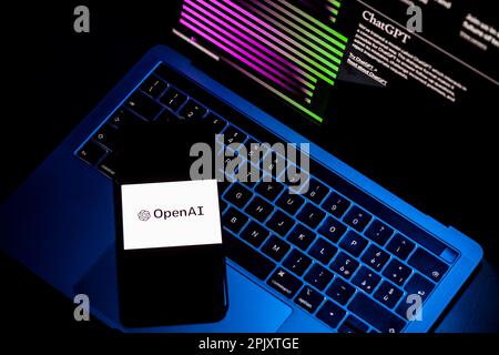 ITALY - March 31, 2023: Laptop screen with Chat Gpt official website. On the illuminated keyboard, a smart phone with the white screen of the logo and Stock Photo