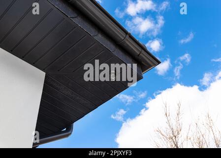 Round wireless camera mounted on the corner of the roof in the soffit, monitoring of a single-family house. Stock Photo