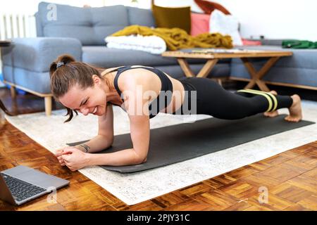 Athletic woman doing plank exercise on yoga mat at home. Stock Photo