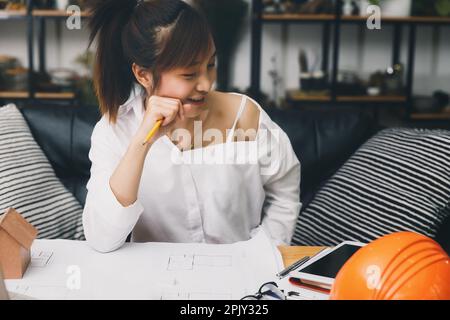 Female architect working on blueprint architects project in office. Stock Photo