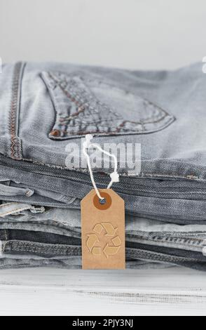 Stack of gray jeans and tag with inscription free on white background Stock Photo