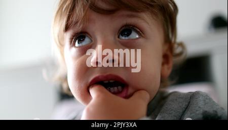Hypnotized little toddler boy watching media cartoon with hand in mouth absorbed in story Stock Photo