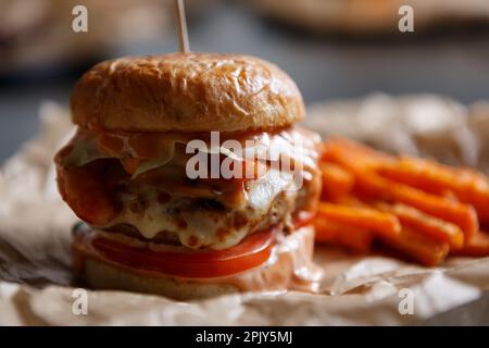 Juicy double cheeseburger for dinner. Large American burger with melted cheese and beef meat served in a diner Stock Photo