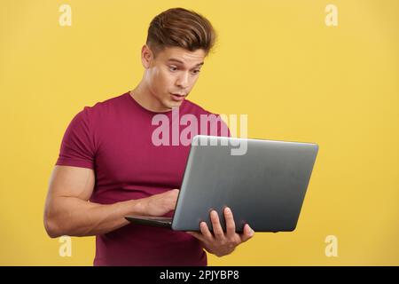 Surprised strong man standing using a laptop Stock Photo