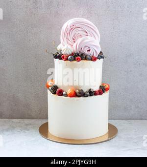 White wedding cake, with slices strawberries, raspberries, blackberry on a white background. Stock Photo