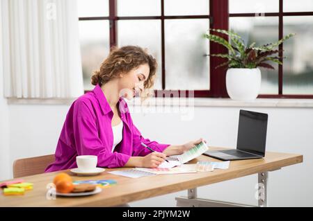 Smiling Designer Woman Working With Color Swatches And Laptop At Home Office, Stock Photo