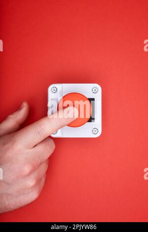 The hand, which pushes the emergency button at the red background at the top view Stock Photo