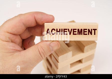 Business concept. A man holds in his hands a wooden block with the inscription - Achievement Stock Photo
