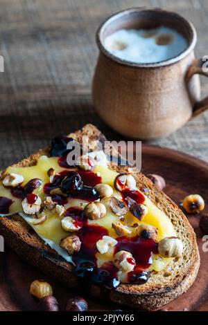 Bread toast with butter, roasted hazelnuts, honey, berry jam on plate ...