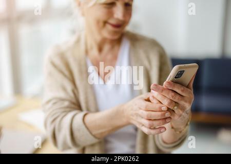 Smiling senior woman using smartphone Stock Photo