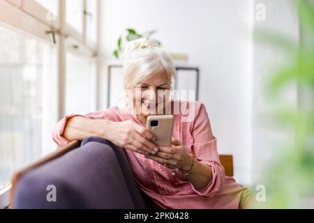 Smiling senior woman using smartphone Stock Photo