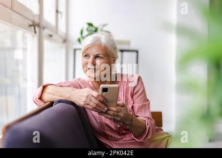 Smiling senior woman using smartphone Stock Photo
