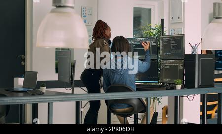 Diverse team of database admins analyzing source code and comparing data script in busy agency room. Cloud programers working on system interface algorithm in development office. Stock Photo