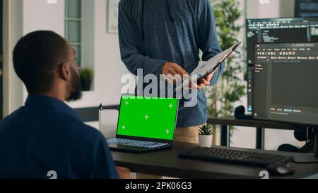 Diverse coders working on code developing and using greenscreen in IT agency office, programming database. Looking at isolated mockup copyspace with chromakey display and template. Stock Photo