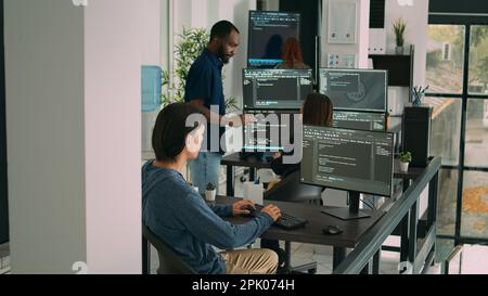 Database programer writing code on computer in software company office, displaying artificial intelligence algorithm. Developer coding system interface and working with data servers. Stock Photo
