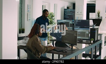 African american focused software engineer working on computer screen and typing in it office. Database programer writing code with algorithms, using new server interface on terminal window. Stock Photo