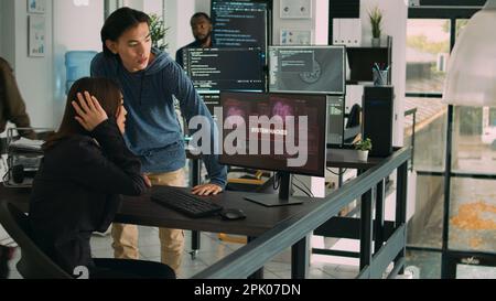 Diverse team of artificial intelligence cloud programers being hacked on firewall server. Web developers looking at critical error on software html script, doing teamwork in agency office. Stock Photo
