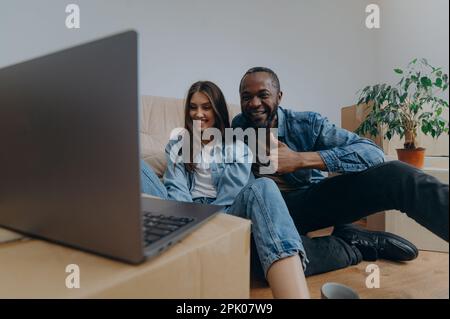 Young couple using laptop in their new house on moving day Stock Photo