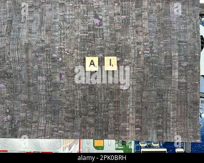 The abrieviation AI spelled out in letter game pieces on a computer motherboard with fuax leather background Stock Photo
