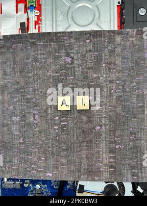 The abrieviation AI spelled out in letter game pieces on a computer motherboard with fuax leather background Stock Photo