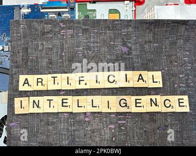 The word Artificial Intelligence spelled out in letter game pieces on a computer motherboard with fuax leather background Stock Photo