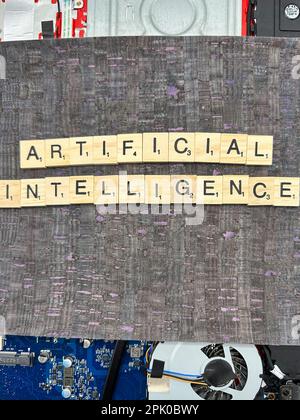 The word Artificial Intelligence spelled out in letter game pieces on a computer motherboard with fuax leather background Stock Photo