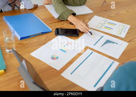 Diverse group of casual architects discussing graphs on table in modern office Stock Photo