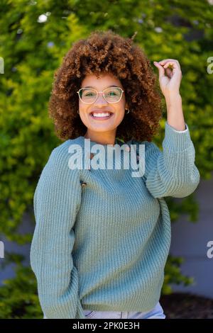 Portrait of happy biracial beautiful young woman with afro hair gesturing while standing in yard Stock Photo