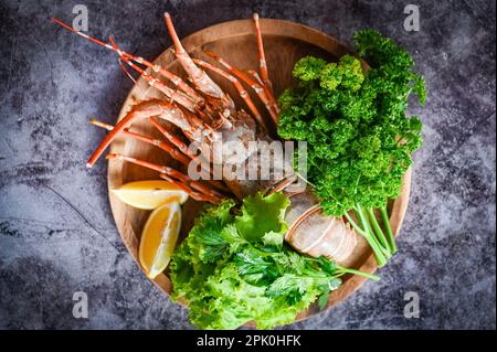 fresh lobster or rock lobster seafood with herb and spices lemon coriander parsley lettuce salad, spiny lobster food on plate, lobster for cooking foo Stock Photo