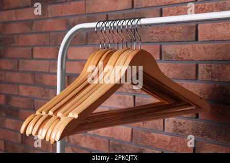 Wooden clothes hangers on rack near red brick wall Stock Photo