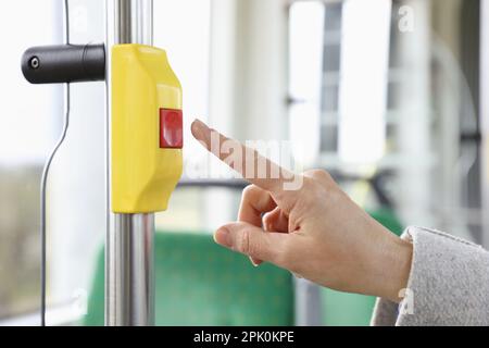 Woman pressing stop button in public transport, closeup Stock Photo