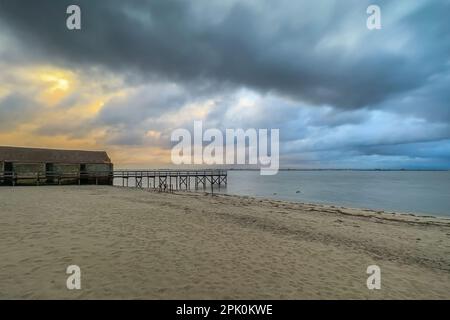 Empty wooden pier to the Ria de Aveiro in Portugal, with dramatic sky and calm water. Torreira, Murtosa - Portugal. Stock Photo