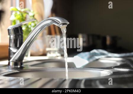 Water running from tap into kitchen sink Stock Photo