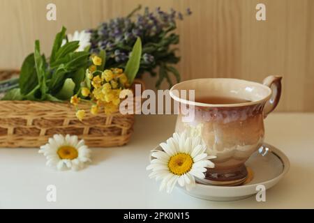 Tasty herbal tea and fresh chamomile flowers on white table, space for text Stock Photo