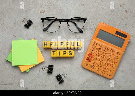 Flat lay composition with text Helpful Tips of yellow cubes on grey table Stock Photo