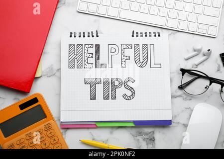 Flat lay composition with text Helpful Tips in notebook on white marble table Stock Photo